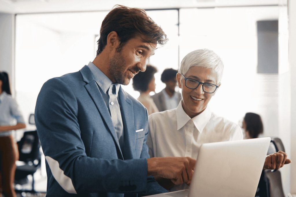 Business man and woman smiling whilst looking at a laptop