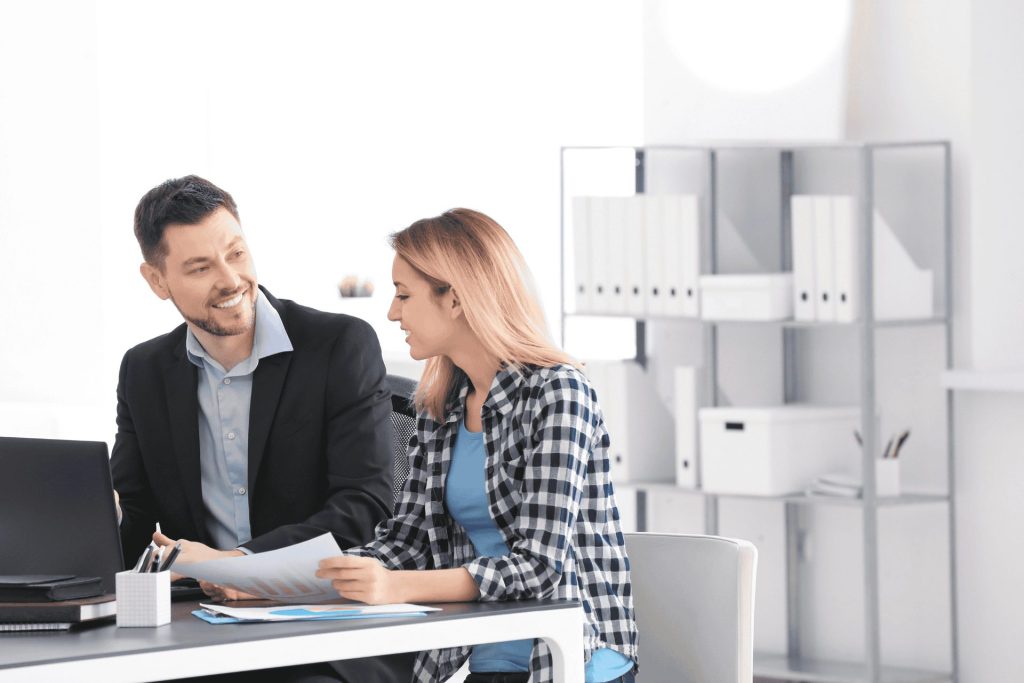Man and woman in an office talking around a laptop