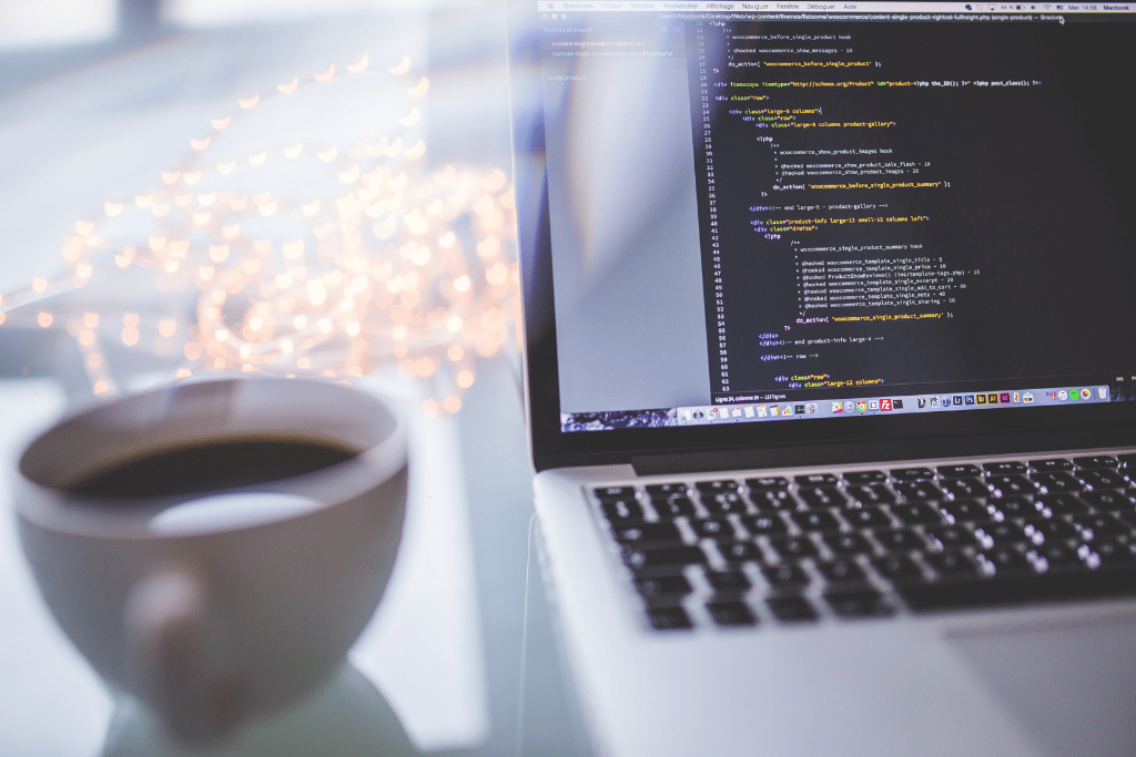 html on a laptop screen next to a cup of coffee